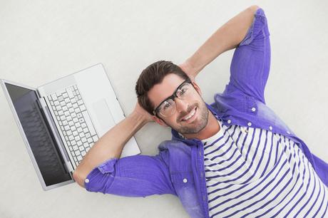Relaxed businessman lying on his laptop in the office