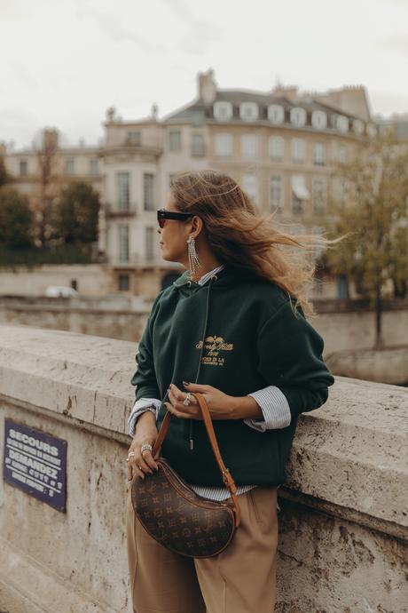 Sara from Collage Vintage at Paris Fashion Week wearing a oversize green sweatshirt, camel trousers, Louis Vuitton vintage bag and sneakers.