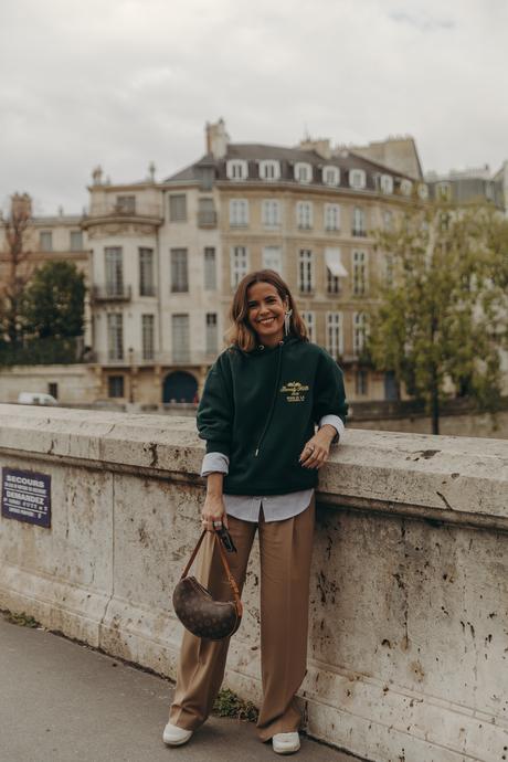 Sara from Collage Vintage at Paris Fashion Week wearing a oversize green sweatshirt, camel trousers, Louis Vuitton vintage bag and sneakers.