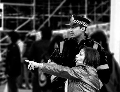 Una mujer con el brazo extendido junto a un policía.