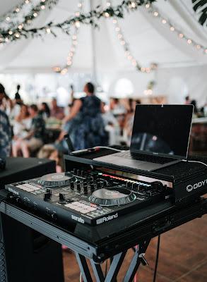Mesa de DJ con fiesta de boda en segundo plano