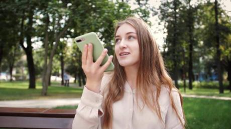 ¿Conocías estos usos de la IA para viajar (lista de herramientas)? Ilustración de una mujer usando su teléfono de voz