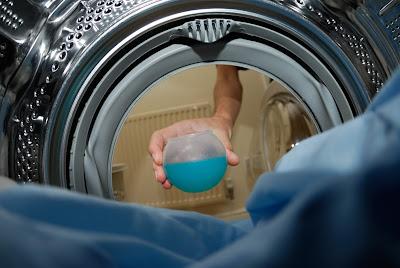 Persona ponienod bola dosificadora de detergente dentro del tambor de la lavadora