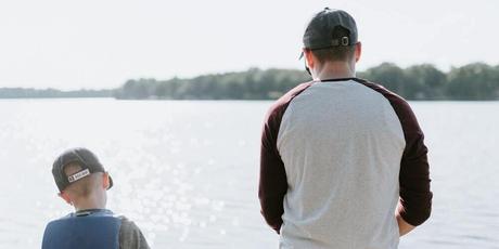 padre e hijo mirando un lago en la naturaleza