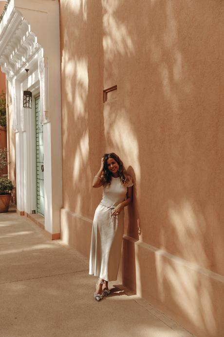 Sara from Collage Vintage wearing a satin long skirt, Mach & Mach crystal embellished pumps and maxi hoops in a palm tree garden in Marrakech