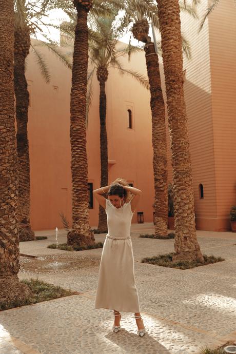 Sara from Collage Vintage wearing a satin long skirt, Mach & Mach crystal embellished pumps and maxi hoops in a palm tree garden in Marrakech