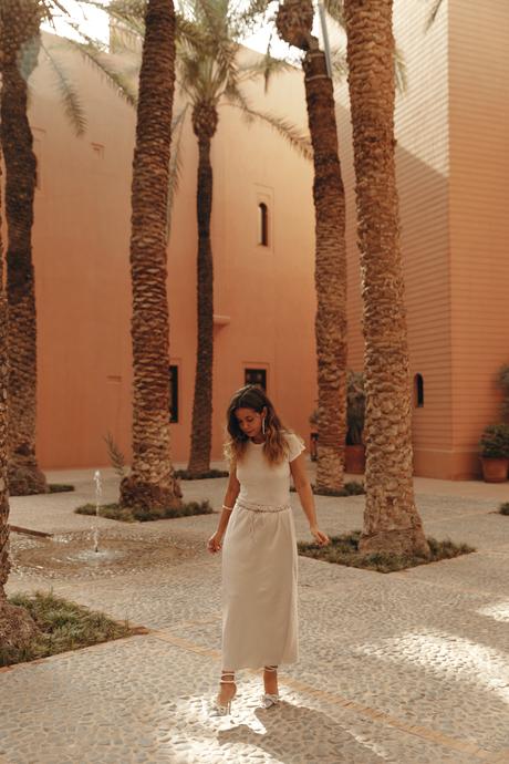 Sara from Collage Vintage wearing a satin long skirt, Mach & Mach crystal embellished pumps and maxi hoops in a palm tree garden in Marrakech