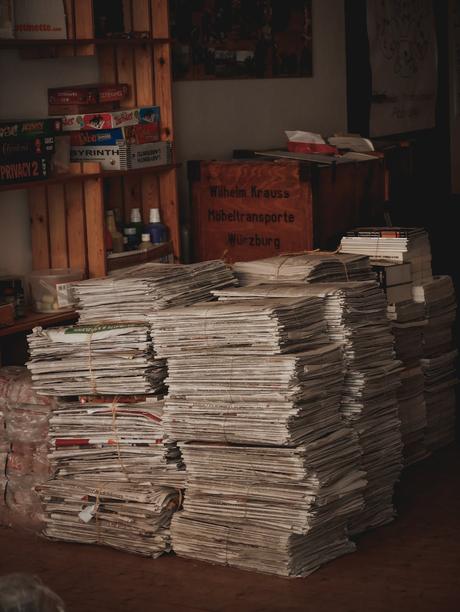 stack of newspapers and board games on a shelf