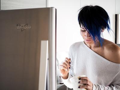 Mujer comiendo un helado delante de la puerta abierta del congelador