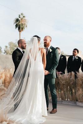 Pareja de novios tomados de la mano delante del maestro de ceremonias