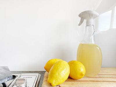 Espray con jugo de limón y limones enteros al lado