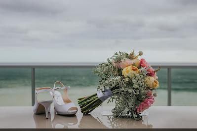 Ramo y zapatos de novia con el mar y el cielo nublado de fondo