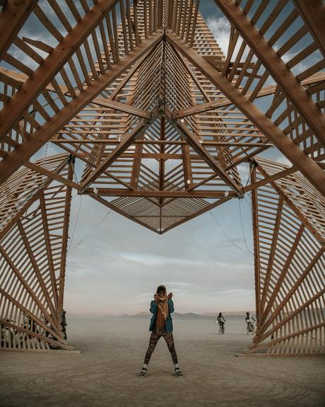 man standing below a wooden structure