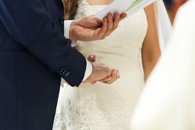 Novio leyendo sus votos de una tarjeta, tomando de la mano a la novia Novio leyendo sus votos de una tarjeta, tomando de la mano a la novia