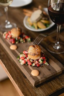 Aperitivos sobre una table junto con un copa de vino y otros alimentos