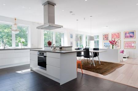 Un salón cocina comedor en dos niveles taburete tolix naranja sofas blancos muebles de ikea estilo sueco decoración estilo nórdico diseño de interiores decoración en blanco decoración de interiores diáfanos cocinas modernas cocinas blancas cocinas abiertas casa sueca en el campo