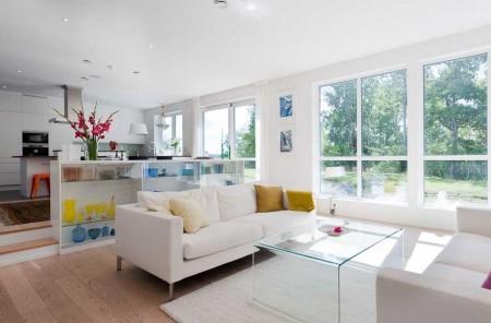 Un salón cocina comedor en dos niveles taburete tolix naranja sofas blancos muebles de ikea estilo sueco decoración estilo nórdico diseño de interiores decoración en blanco decoración de interiores diáfanos cocinas modernas cocinas blancas cocinas abiertas casa sueca en el campo