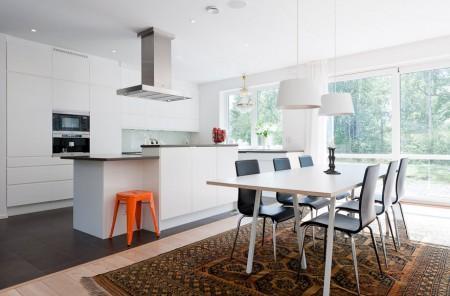 Un salón cocina comedor en dos niveles taburete tolix naranja sofas blancos muebles de ikea estilo sueco decoración estilo nórdico diseño de interiores decoración en blanco decoración de interiores diáfanos cocinas modernas cocinas blancas cocinas abiertas casa sueca en el campo