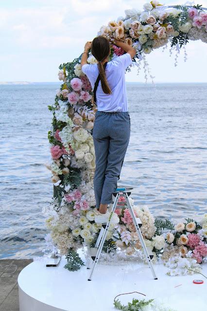 Mujer preparando un arco de flores para una boda en la playa