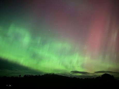 ¿Qué causa los diferentes colores de la aurora? Un experto explica el arcoíris eléctrico Un cielo nocturno moteado con luces verdes brillantes y rayas rosas encima.