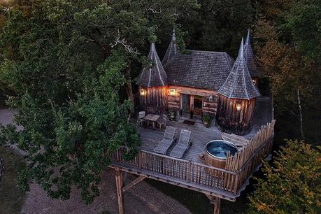 Vista por drones de la casa del árbol de Cabane Monbazillac al atardecer con las luces encendidas y el baño nórdico descubierto