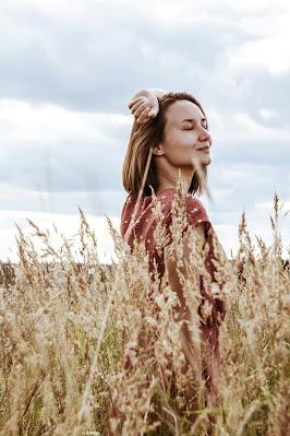 Mujer con los ojos cerrados y sonriente disfrutando en un campo de espigas Mujer con los ojos cerrados y sonriente disfrutando en un campo de espigas