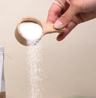 Persona con cacito de detergente en polvo vertiéndolo sobre una camiseta