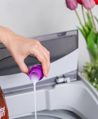 Persona vertiendo detergente líquido en el tambor de la lavadora Persona vertiendo detergente líquido en el tambor de la lavadora