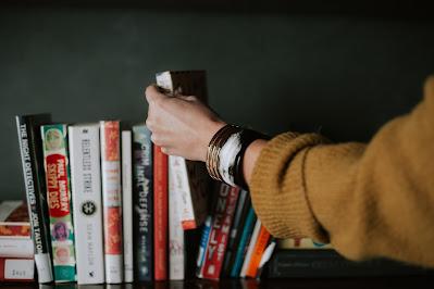 Mujer tomando libros de una estantería Mujer tomando libros de una estantería