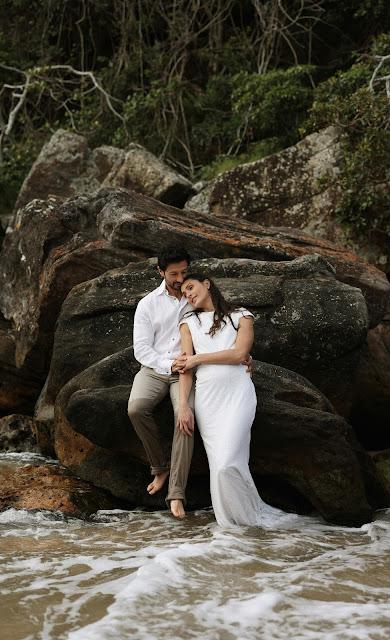 Novios posando en la playa, ella con un vestido recto y sencillo Novios posando en la playa, ella con un vestido recto y sencillo