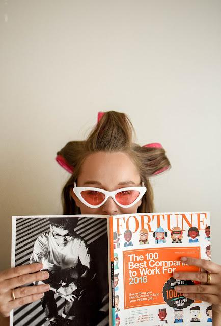 Mujer sentada con rulos, gafas y leyendo una revista Mujer sentada con rulos, gafas y leyendo una revista