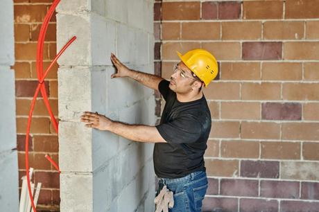 man in black t shirt and blue denim jeans holding a concrete wall