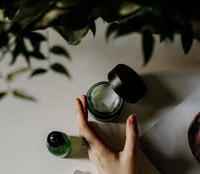 Mujer tomando un tarro de crema con la mano