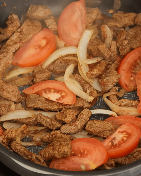 carne con cebolla y tomate en sartén