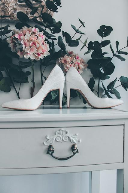 Zapatos de novia blancos sobre una cómoda Zapatos de novia blancos sobre una cómoda
