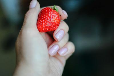 Mano con manicura natural sosteniendo una fresa