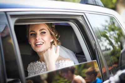 Novia sonriendo dentro del coche nupcial