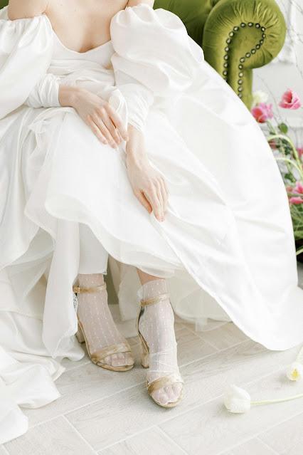 Novia sentada con un vestido voluminoso y mostrando calcetines y sandalias