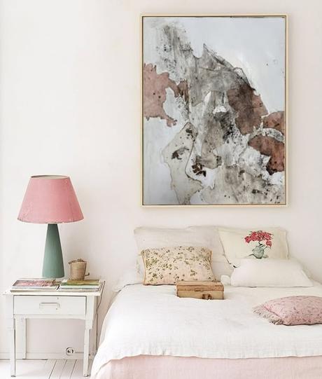 Dormitorio acogedor con obra abstracta de la serie Fuego, en tonos rojizos y grises, que evoca transformaciĂłn y renovaciĂłn.