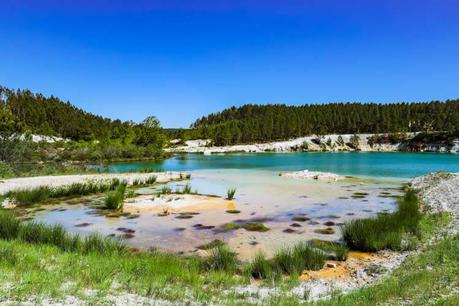 Lac Bleu de Guizengeard: camina a los lagos azules secretos de Charente El borde arenoso en el lago más verde donde las hierbas han comenzado a crecer desde los depósitos de arena y arcilla que forman pequeñas islas en Lac Bleu de Guizengeard