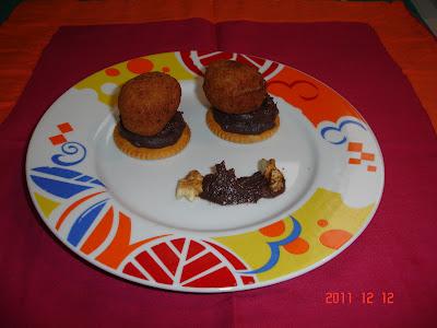 Bolitas de Mouse de patata con queso y nueces sobre cama de frijoles negros molidos con cebolla caramelizada.