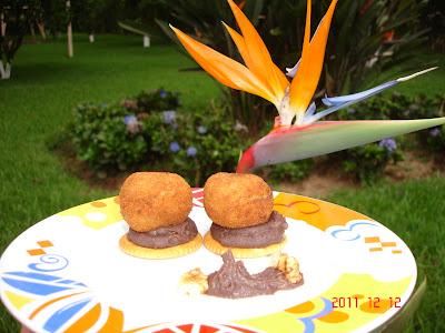 Bolitas de Mouse de patata con queso y nueces sobre cama de frijoles negros molidos con cebolla caramelizada.