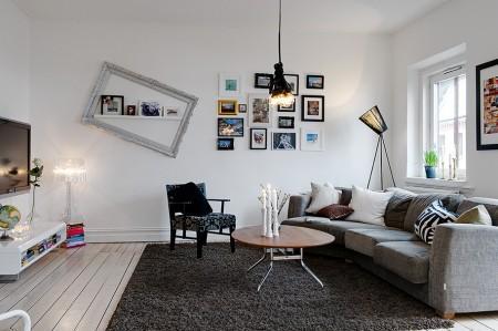 suelo madera negro sofá gris papel de pared negro con círculos papel de pared gris de cachemir muebles de diseño nórdico lámpara de bombillas estilo nórdico decoración espacio diáfano diseño de interiores decoración nórdica escandinava decoración de interiores decoración de espacios pequeños decoración con espejos cocina comedor salón unidos chandelier dorado 