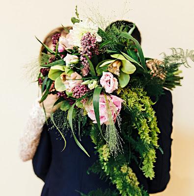 Novios abrazándose y ramo en primer plano