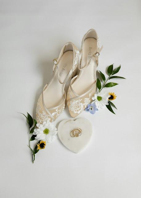 Zapatos de nova junto a unas flores y unos anillos