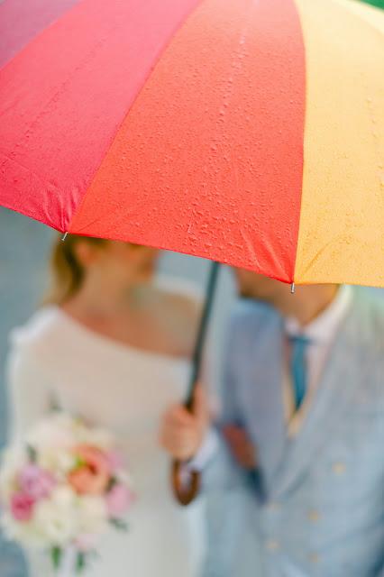 Pareja de novios bajo un paraguas multicolor Pareja de novios bajo un paraguas multicolor