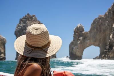 Mujer mirando al mar y la playa con un sombrero Mujer mirando al mar y la playa con un sombrero
