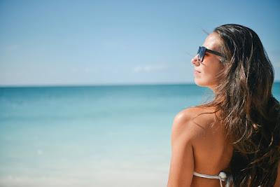 Mujer con una larga melena y gafas de sol en la playa Mujer con una larga melena y gafas de sol en la playa