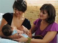 Fotografía de una IBCLC ayudando a otra madre a amamantar a su bebé