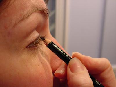 Mujer utilizando un lápiz de ojos Mujer utilizando un lápiz de ojos